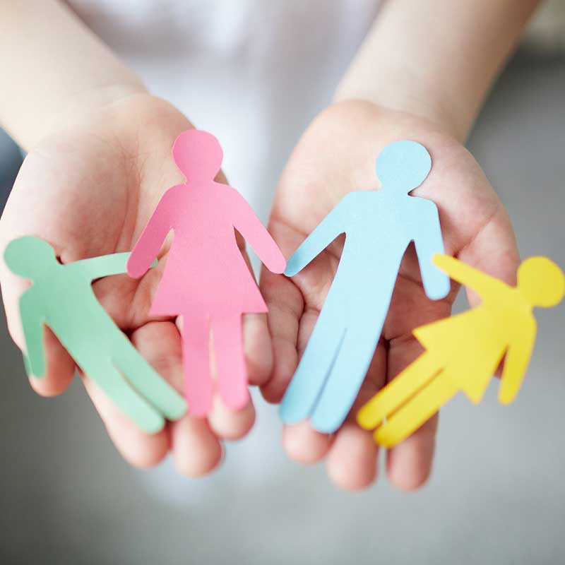 Nahaufnahme von Händen, die eine Familie aus Papierfiguren zeigt